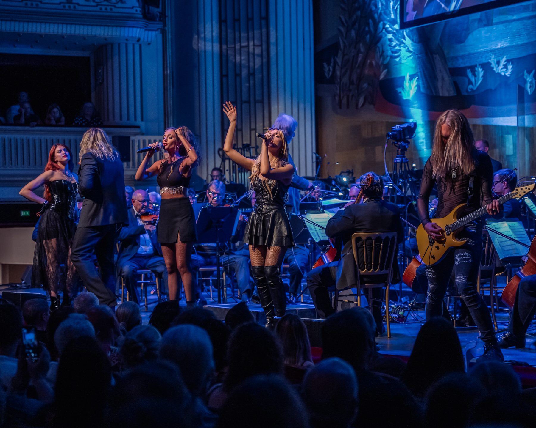 Singers and guitarist on a blue-lit stage