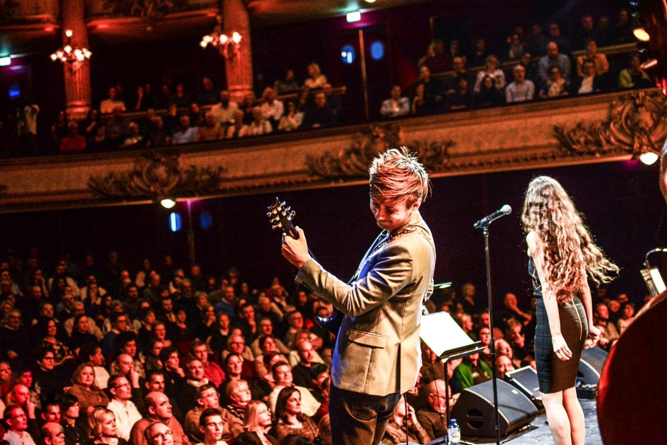 Guitarist and singer in front of a full theatre