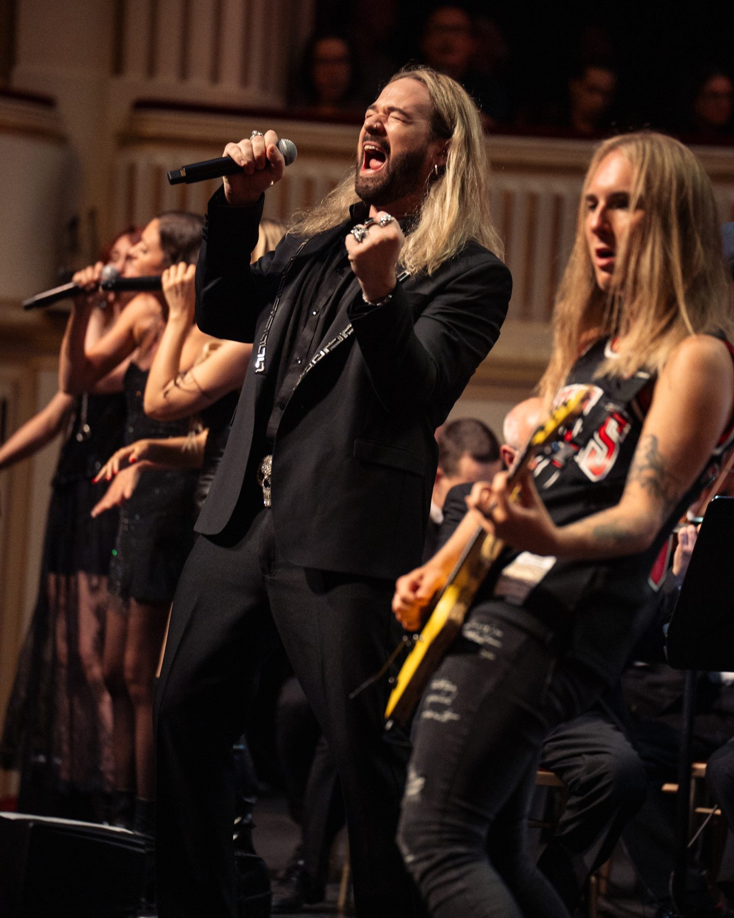 Singer and guitarist in front of the orchestra