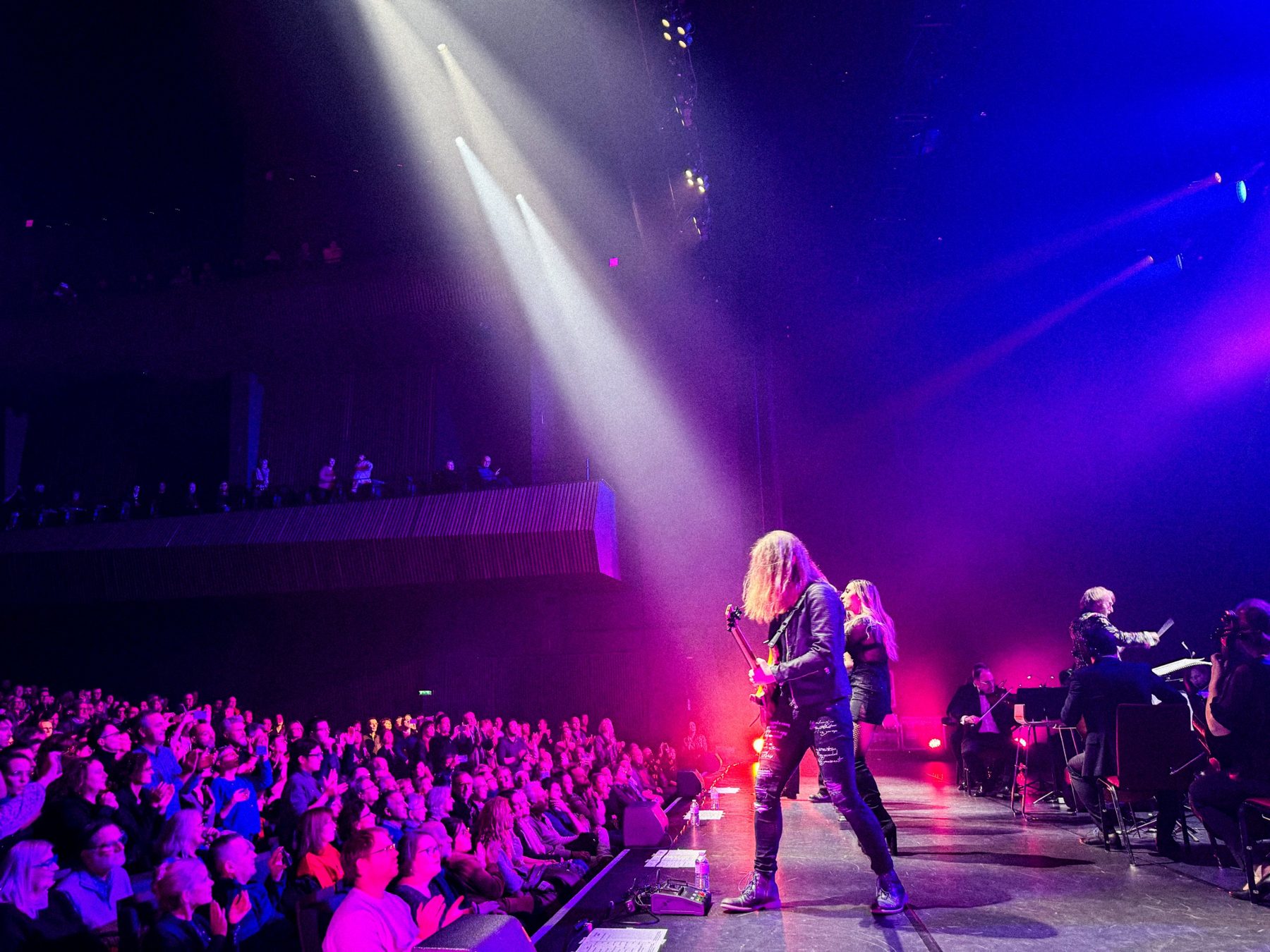Guitarist and singer under spotlights in front of a full hall